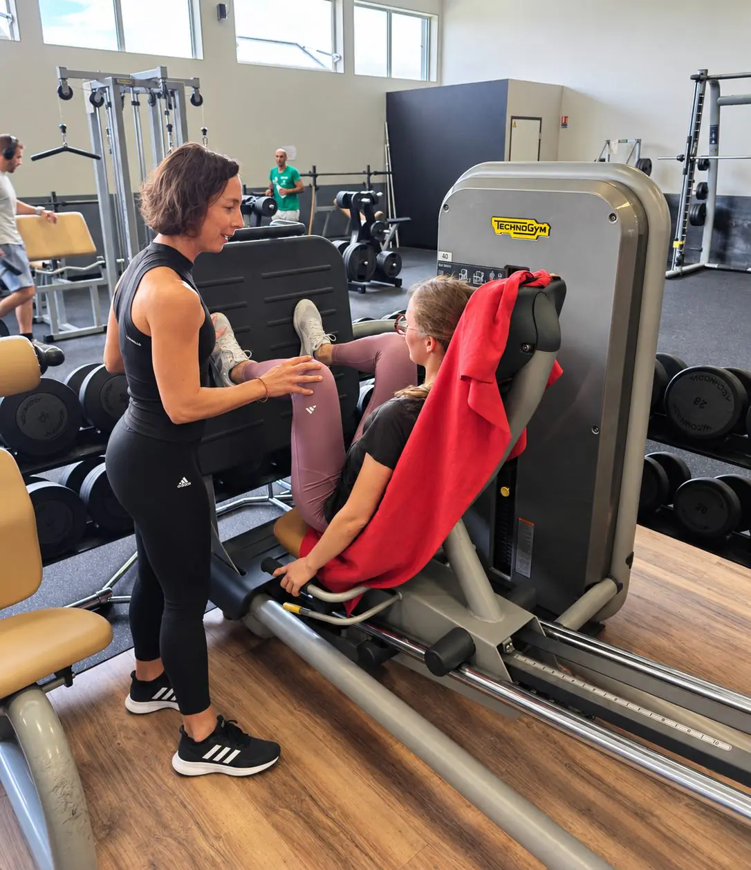 Séance de coaching personnalisé au Garden Fitness : une coach guide une adhérente sur la presse à cuisses